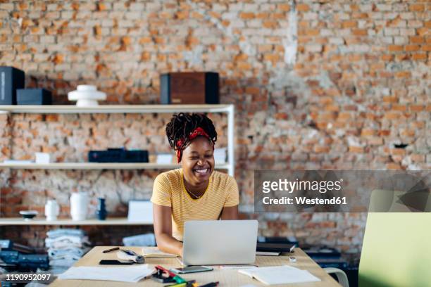 happy young woman sitting at table with laptop - founder stock pictures, royalty-free photos & images