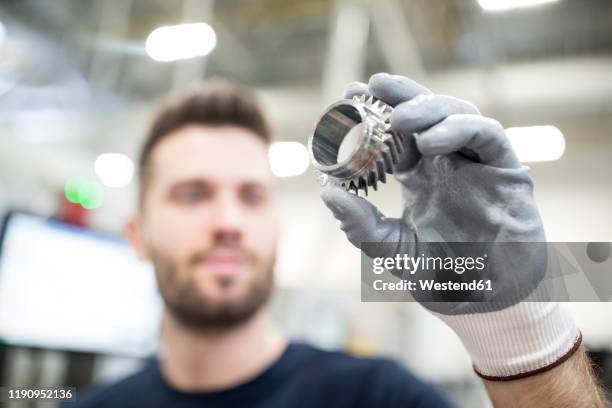 close-up of man holding workpiece in a factory - glove stock-fotos und bilder