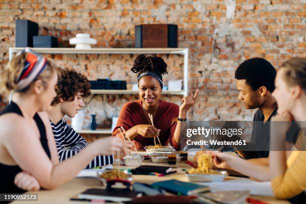 young people sitting together at table having lunch break - lunch stock-fotos und bilder