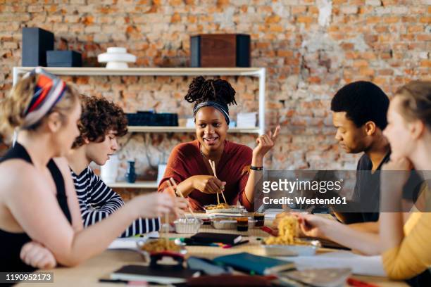 young people sitting together at table having lunch break - office lunch stock pictures, royalty-free photos & images