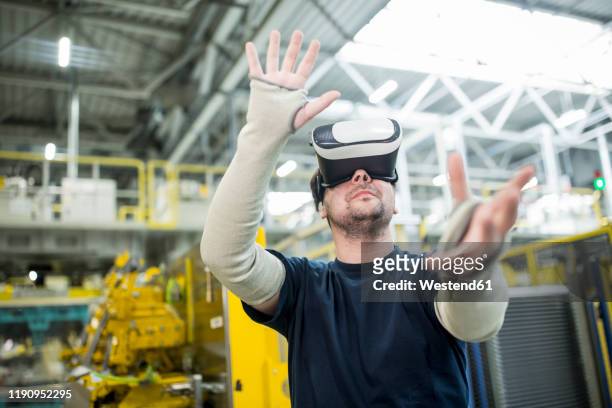 man wearing vr glasses in modern factory - car industry stock pictures, royalty-free photos & images