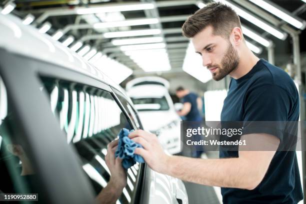 man working in modern car factory wiping finished car - autofabrik stock-fotos und bilder