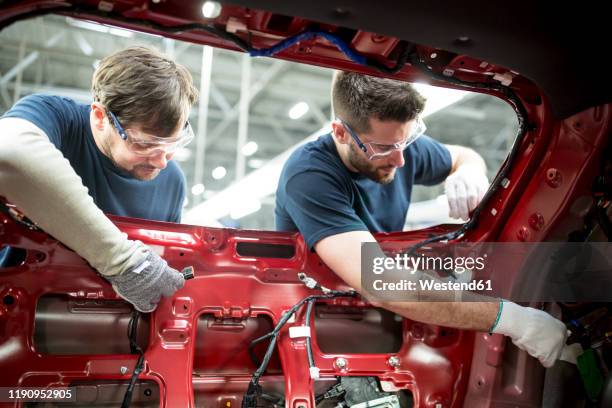 two colleagues working at bodywork in modern car factory - car plant stock pictures, royalty-free photos & images