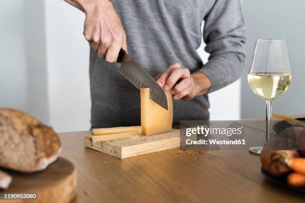 close-up of man cutting cheese on kitchen counter - hombre cortando queso fotografías e imágenes de stock