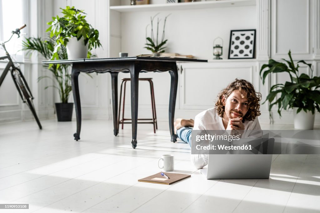 Man lying on the floor at home using laptop