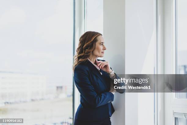 mature businesswoman looking out of window in office - soul searching stock pictures, royalty-free photos & images