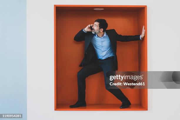 mature businessman on cell phone caught in a niche - constraints stock-fotos und bilder