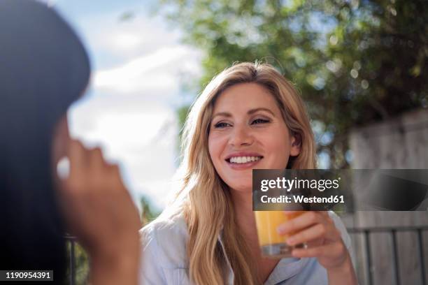 two women having breakfast at outdoor cafe table, having fun, talking - orangensaft stock-fotos und bilder