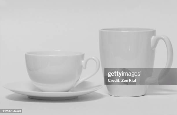 white ceramic coffee mug next to a tea cup and saucer against white background - blank coffee cup stock-fotos und bilder