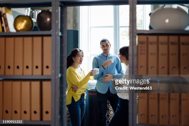 coleagues chatting and drinking coffee in office kitchenet - gossip stock pictures, royalty-free photos & images