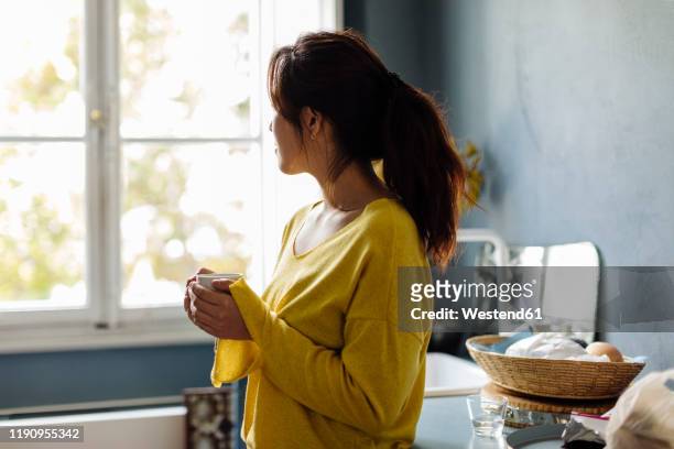 woman drinking tea in office kitchenet - asian drinking tea stock pictures, royalty-free photos & images