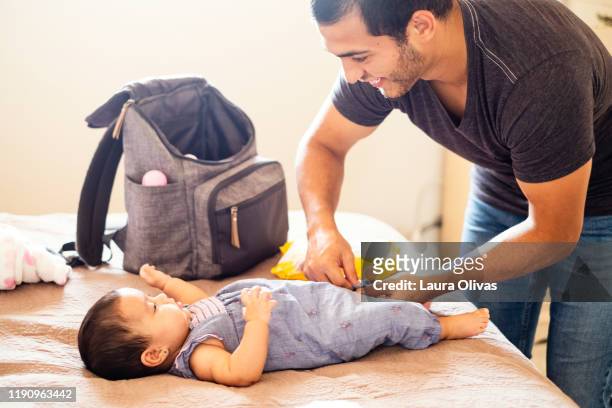 young father changes diaper of his infant daughter - diaper bag stockfoto's en -beelden