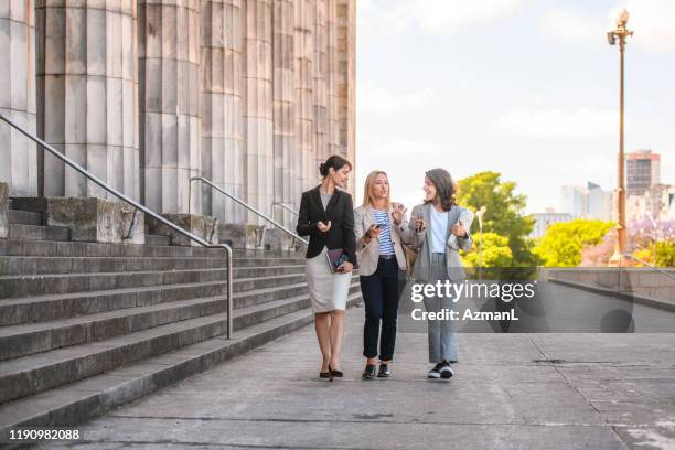 female law classmates walking and talking with smart phone - law school stock pictures, royalty-free photos & images
