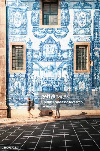 woman walking in porto against azulejos wall of the capela das almas church in porto - iacomino portugal stock pictures, royalty-free photos & images