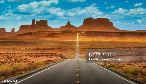 view of historic u.s. route 163 running through famous monument valley in beautiful golden evening light at sunset on a beautiful sunny day with blue sky in summer, utah, usa - utah stock-fotos und bilder