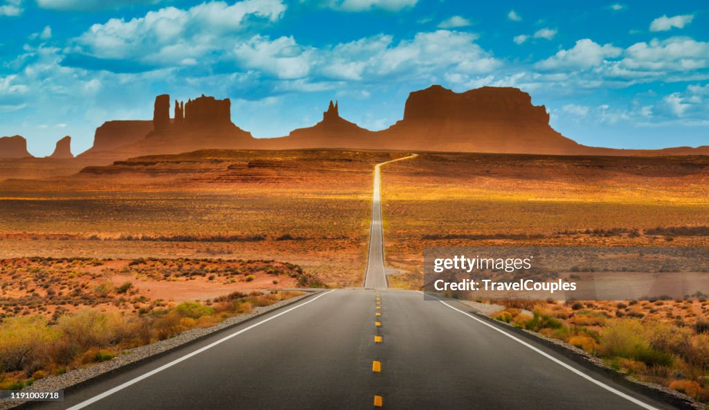 View of historic U.S. Route 163 running through famous Monument Valley in beautiful golden evening light at sunset on a beautiful sunny day with blue sky in summer, Utah, USA