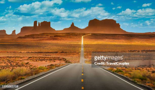 view of historic u.s. route 163 running through famous monument valley in beautiful golden evening light at sunset on a beautiful sunny day with blue sky in summer, utah, usa - utah landscape stock pictures, royalty-free photos & images