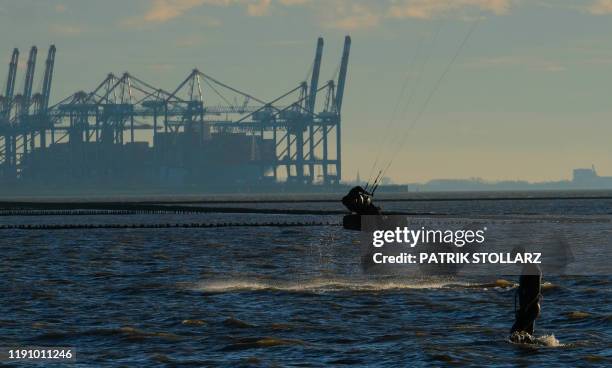 Kite surfers use the wind as the sun shines at the North Sea in Bremen, northern Germany, on December 30, 2019.