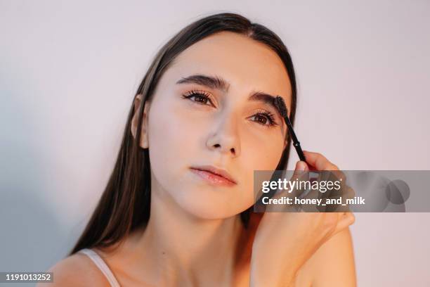 woman brushing her eyebrows - eyebrow fotografías e imágenes de stock