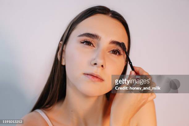 woman brushing her eyebrows - eyebrow stock pictures, royalty-free photos & images