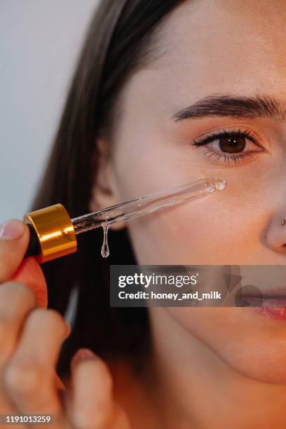 close-up of a woman applying serum to her face - serum stock pictures, royalty-free photos & images