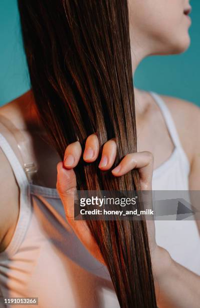 woman applying oil to her hair - human hair stockfoto's en -beelden