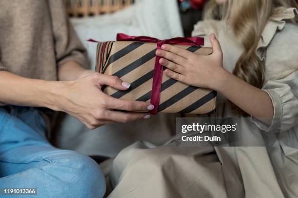close-up of a mother giving her daughter a gift - child giving gift stock-fotos und bilder