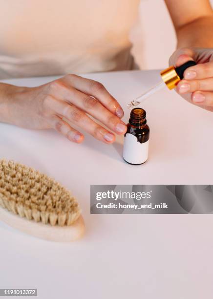 woman applying cuticle oil to her nails - cutícula fotografías e imágenes de stock