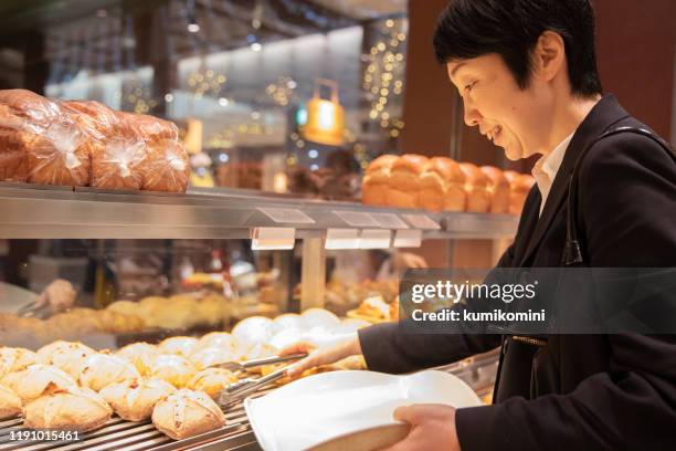 vrouw die breat bij bakery koopt - supermarket bread stockfoto's en -beelden