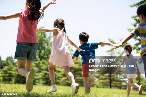 happy chinese children playing on meadow - 飛行機のまね ストックフォトと画像