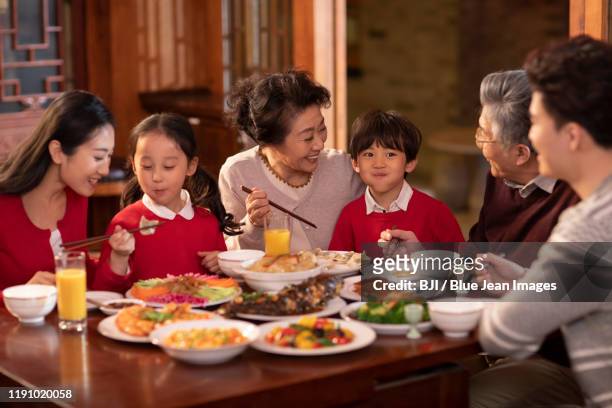 happy chinese family eating dinner for chinese new year - wiedersehenstreffen stock-fotos und bilder