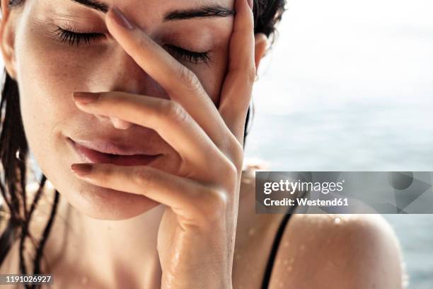 woman with eyes closed and hand on her face after bathing, close-up - woman washing face stockfoto's en -beelden