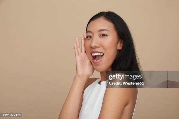 portrait of young female chinese woman, open mouth - portrait beige background stock pictures, royalty-free photos & images