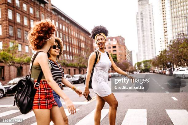 three young women walking on city street - buenos aires city stock pictures, royalty-free photos & images