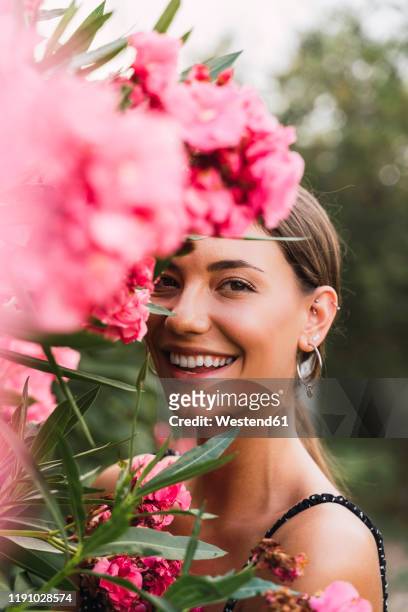 portrait of laughing young woman in a park with pink blossoming flowers - earring stud stock pictures, royalty-free photos & images