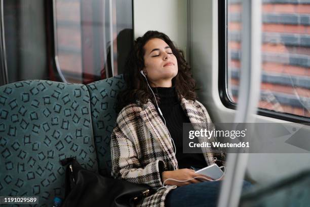 young woman with closed eyes relaxing on a subway - headphones eyes closed stock pictures, royalty-free photos & images