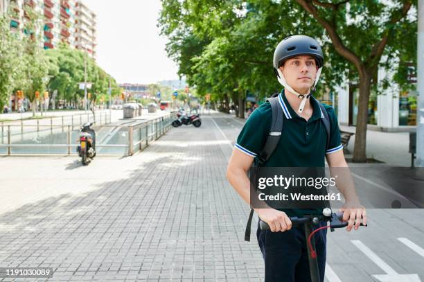 casual young businessman riding e-scooter on bicycle lane in the city - e scooter stock-fotos und bilder
