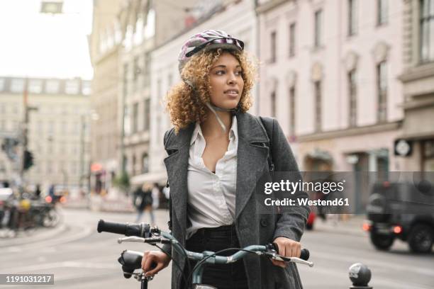 woman with bicycle in the city, berlin, germany - cycling helmet photos et images de collection