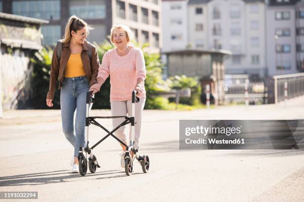 granddaughter and her grandmother walking on footbridge - rollator stock-fotos und bilder