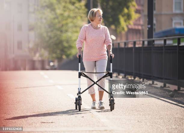 senior woman with wheeled walker on footbridge - mobility walker stock pictures, royalty-free photos & images