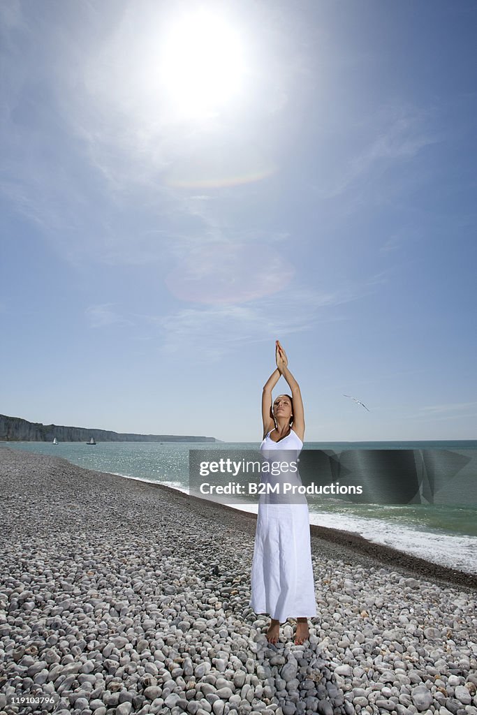 Young woman performing yoga on beach
