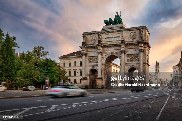 victory gate with city traffic, munich, bavaria, germany - munich stock pictures, royalty-free photos & images