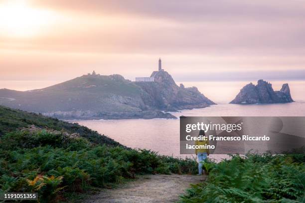 woman watching at faro cabo vilano (cape vilan lighthouse) at sunset, galicia, spain. - a coruna stock-fotos und bilder