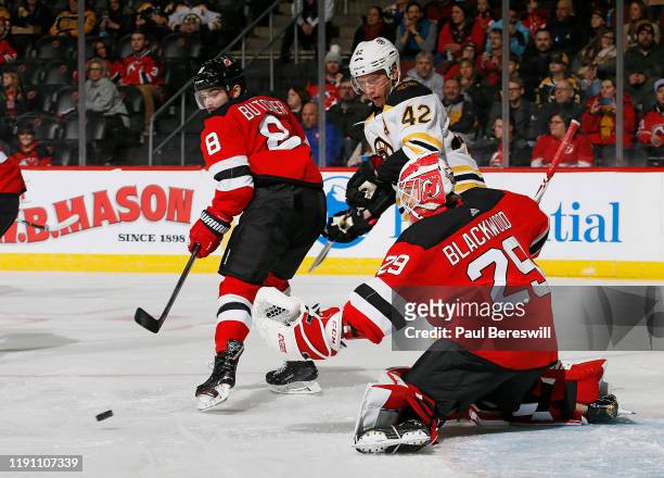 Goalie Mackenzie Blackwood of the New Jersey Devils makes a save on a shot by David Backes of the Boston Bruins as Devils Will Butcher helps defend...