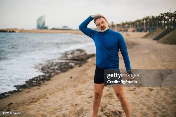 man stretching his neck while exercising on the beach - neck stretch stock pictures, royalty-free photos & images