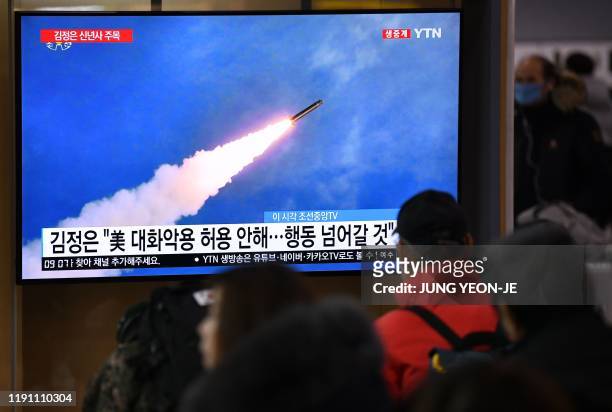 People watch a television news programme showing file footage of North Korea's missile test, at a railway station in Seoul on January 1, 2020. -...