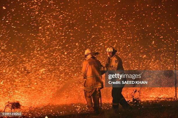 This picture taken on December 31, 2019 shows firefighters struggling against the strong wind in an effort to secure nearby houses from bushfires...