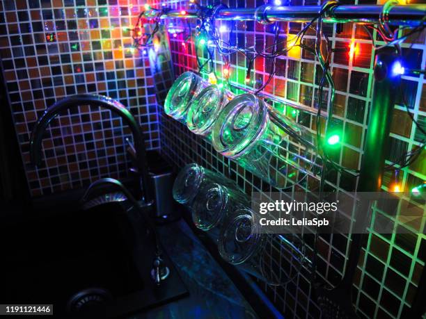 glasses lit by a garland in the new year's kitchen. - brightly lit imagens e fotografias de stock