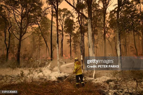 Firefighter sprays foam retardant on a back burn ahead of a fire front in the New South Wales town of Jerrawangala on January 1, 2020. - A major...