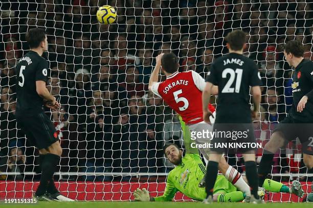 Arsenal's Greek defender Sokratis Papastathopoulos shoots past Manchester United's Spanish goalkeeper David de Gea to score their second goal during...